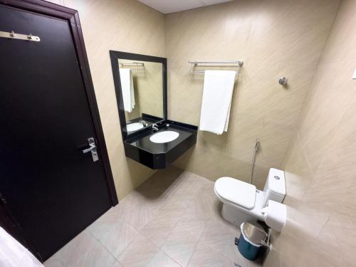 y baño con aseo, lavabo y espejo. en Royal Residence Hotel Apartments, en Umm Al Quwain