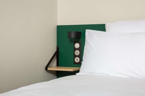 1 cama con cabezal verde y almohada blanca en Best Western 11BAUER Paris Saint-Ouen, en Saint-Ouen