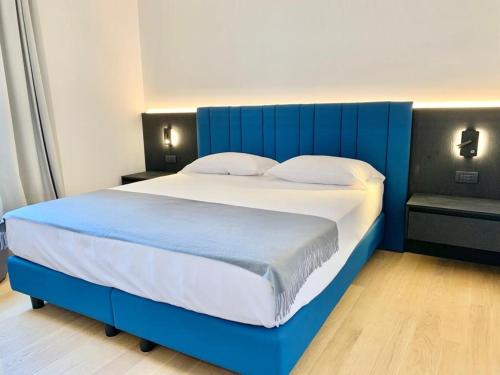 een groot bed met een blauw hoofdeinde in een slaapkamer bij Domo Apuliae Aparthotel in Bari