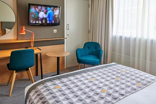 a room with a bed and two chairs and a television at Holiday Inn Southampton, an IHG Hotel in Southampton