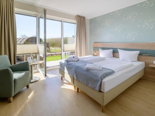 um quarto com uma cama, uma cadeira e janelas em Nordsee-Hotel Arlau-Schleuse em Husum