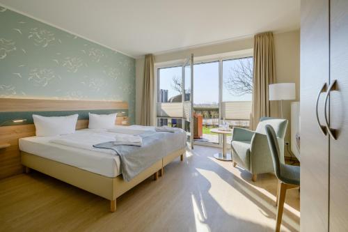 um quarto de hotel com uma cama e uma cadeira em Nordsee-Hotel Arlau-Schleuse em Husum