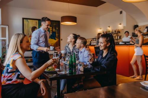 een groep mensen die rond een tafel in een restaurant zitten bij Hotel Merkur - Czech Leading Hotels in Praag