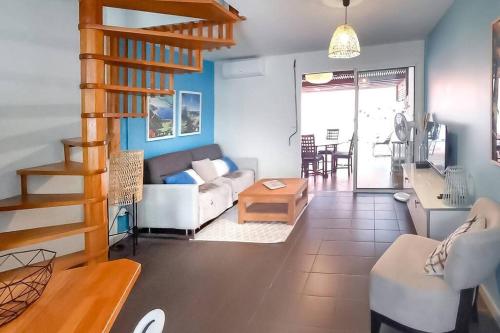 ein Wohnzimmer mit einem Sofa und einem Tisch in der Unterkunft COTTAGE BLUE - Villa 4 personnes - 2 chambres - accès direct à la plage et à l'esplanade de Boucan Canot avec ses bars et restaurants in Saint-Gilles-les-Bains