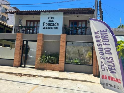 una señal frente a un edificio con bandera en Pousada Velas do Forte, en Cabo Frío