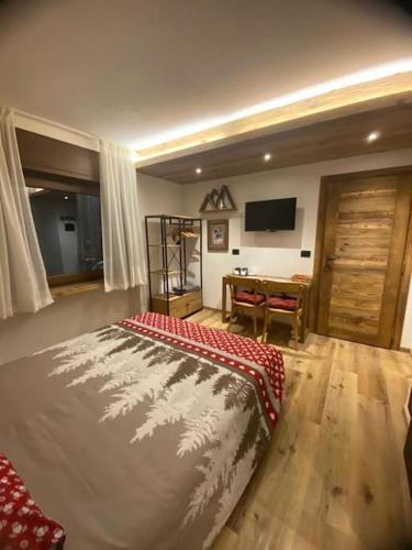 een slaapkamer met een bed en een tafel met een televisie bij La Chambre de Chaloz in Valtournenche