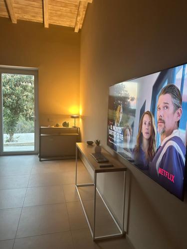 una TV a schermo piatto appesa a un muro in soggiorno di MP Luxury House a Budoni