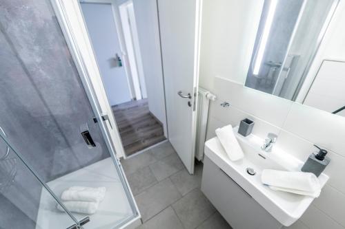 y baño blanco con lavabo y ducha. en Hökis-Zimmervermietung 9 mit Küchenzeile, en Brande-Hörnerkirchen