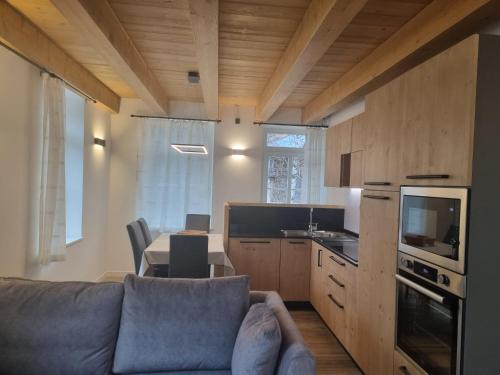 een woonkamer met een bank en een tafel en een keuken bij Appartamento Vale e Schena Cortina 4 posti letto in San Vito di Cadore