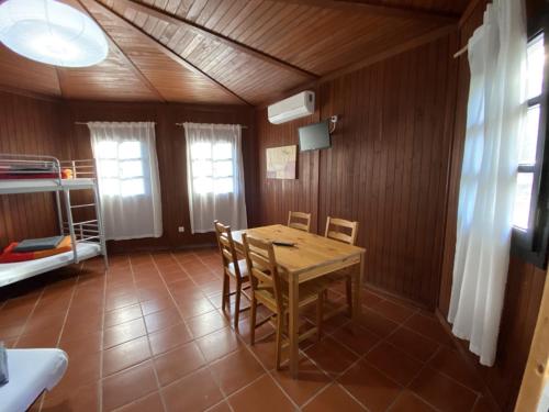 ein Esszimmer mit einem Tisch, Stühlen und einem Etagenbett in der Unterkunft YMCA Camp Alambre in Azeitão