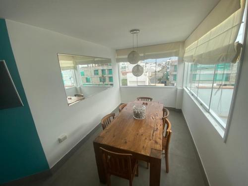 a dining room with a wooden table and some windows at Playa Norte Experience in Punta Hermosa