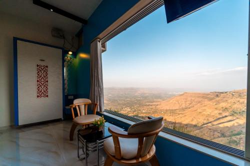 Habitación con ventana grande con sillas y vistas. en Treebo Raval Resort with Valley View, en Panchgani