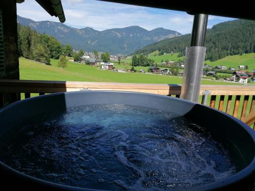 d'un bain à remous sur une terrasse couverte offrant une vue sur les montagnes. dans l'établissement Ferienhaus Asterbach, à Gosau