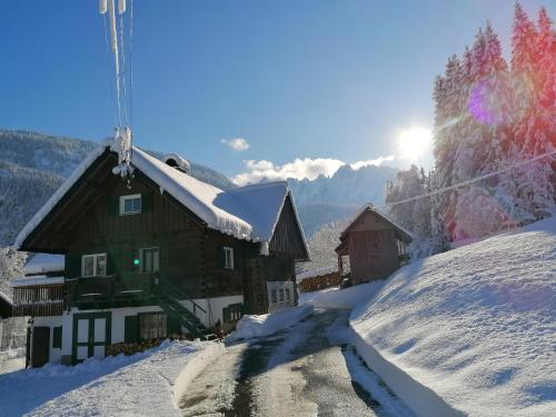 une maison sur une montagne enneigée avec le soleil en arrière-plan dans l'établissement Ferienhaus Asterbach, à Gosau