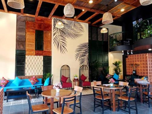 a restaurant with tables and chairs and a wall with a palm tree mural at Tam Coc Lion Kings Hotel & Resort in Ninh Binh