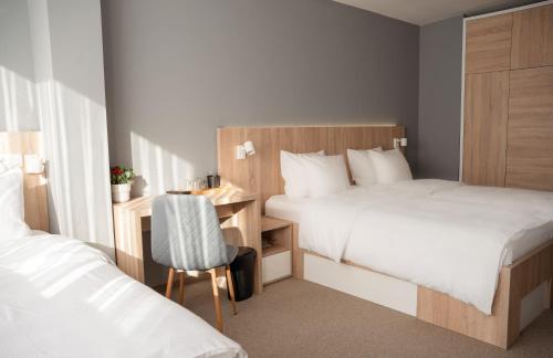 a bedroom with two beds and a desk and a chair at Olivia Rooms in Belgrade