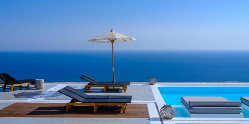 una piscina con sedie e ombrellone accanto a una piscina di Terra Blanca Suites a Imerovigli