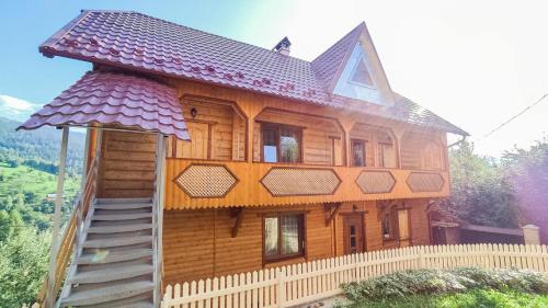 una gran casa de madera con una valla delante de ella en Котедж Біля лісу, en Yaremche