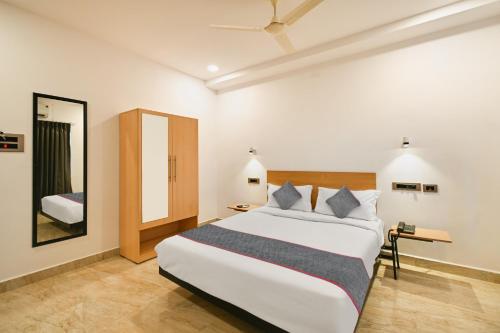 - une chambre avec un grand lit blanc et un miroir dans l'établissement Super Townhouse De Alphabet Karmanghat, à Hyderabad