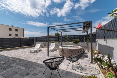 a patio with chairs and a fountain and a fence at luxury apartment with garden jacuzzi in Trogir