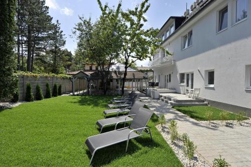 eine Reihe von Bänken im Gras neben einem Gebäude in der Unterkunft Villa Oliver 1 Siófok in Siófok