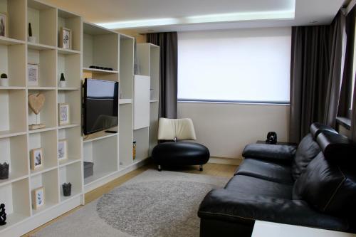 sala de estar con sofá de cuero negro y TV en Strasbourg Entzheim, en Entzheim