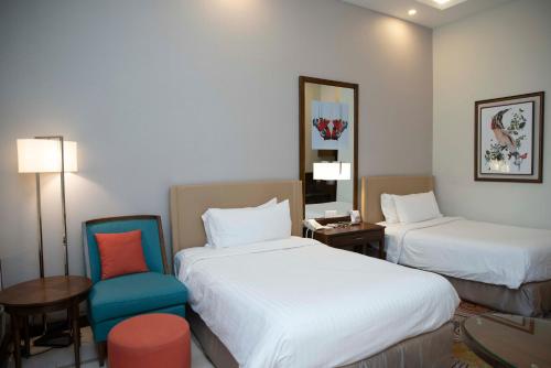 um quarto de hotel com duas camas e uma cadeira em Pearl Continental Hotel, Bhurban em Bhurban