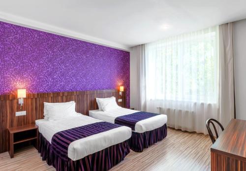 una camera d'albergo con due letti e una parete viola di Rija VEF Hotel with FREE Parking a Riga