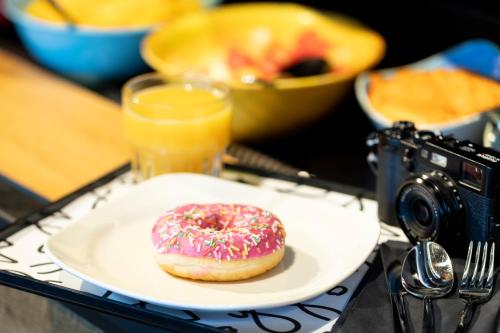 un donut sur une plaque sur une table avec une caméra dans l'établissement Moxy Brussels City Center, à Bruxelles