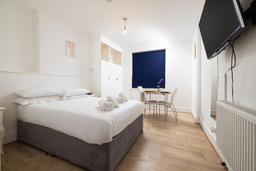 a bedroom with a bed and a tv and a table at Charmstay Swiss Cottage in London