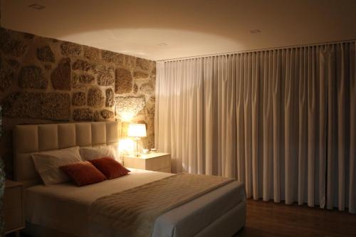 - une chambre avec un grand lit et un mur en pierre dans l'établissement Vila de Campos - Gerês, à Vieira do Minho