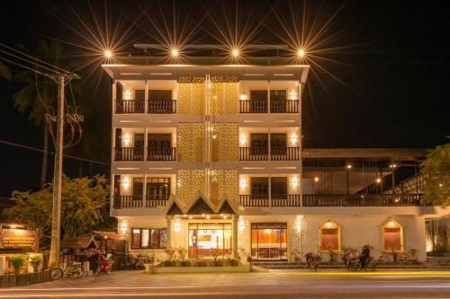 um edifício branco alto com luzes acesas à noite em LuangPrabang Center Hotel em Luang Prabang