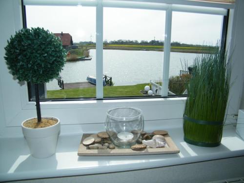 alféizar de la ventana con un plato de rocas y un jarrón de cristal en Ferienwohnung Seeblick - b47745, en Neuharlingersiel