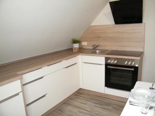 una pequeña cocina con armarios blancos y fregadero en Ferienwohnung Seeblick - b47745, en Neuharlingersiel