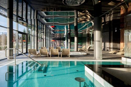 uma piscina num edifício com cadeiras em Złoty Horyzont Hotel & Resort Szklarska Poręba em Szklarska Poręba