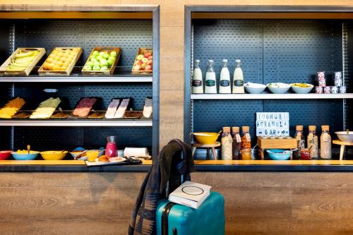 a suitcase sitting on a bench in front of a shelf of food at Moxy Southampton in Southampton