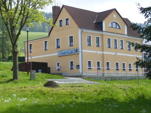 ein großes gelbes Gebäude mit einem Schild drauf in der Unterkunft „Frische Quelle“ Jonsdorf in Kurort Jonsdorf