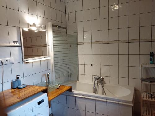 ein weiß gefliestes Bad mit einer Badewanne und einem Waschbecken in der Unterkunft Apartmán v dřevěném domě in Franzensbad