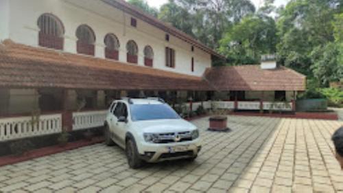 a white car parked in front of a building at Keloth Tharavad Kerala in Panamaram