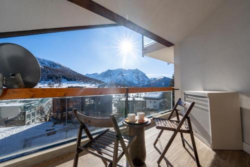 a room with two chairs and a large window with mountains at [SESTRIERE] Appartamento sulle piste in Sestriere