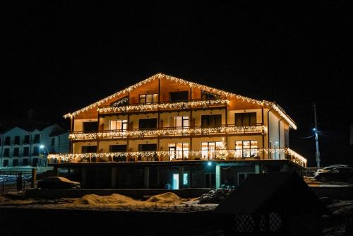 un grand bâtiment avec des lumières allumées la nuit dans l'établissement Yo Hotel, à Bukovel