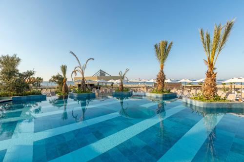 uma piscina com palmeiras e guarda-sóis em Kirman Belazur Resort & Spa em Belek