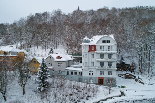 een groot wit huis met sneeuw erop bij Hotel Dagmar in Jáchymov