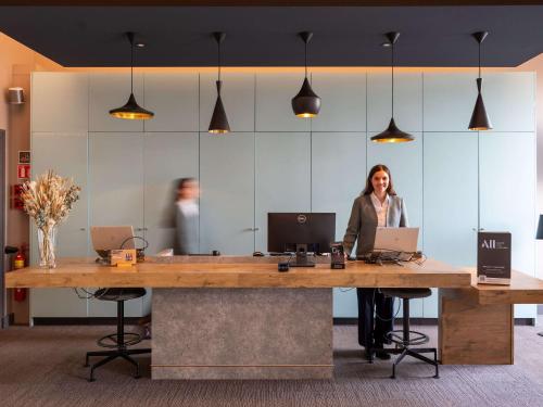 a woman standing at a large desk with two laptops at ibis Lyon Centre Perrache in Lyon