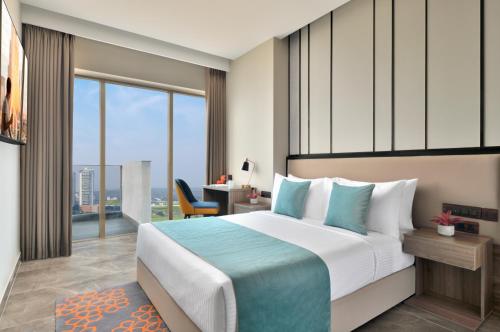 a hotel room with a large bed and a desk at Citadines Paras Square Gurugram in Gurgaon