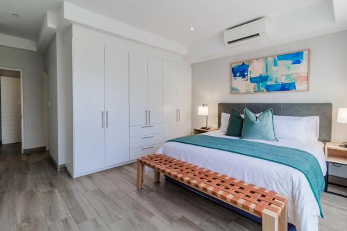 a bedroom with a large bed and a bench at STAY Menlyn in Pretoria