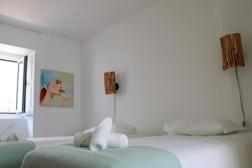 een witte slaapkamer met 2 bedden en een schilderij aan de muur bij Casa dos Cucos in Ericeira