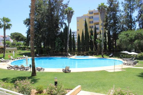 a large swimming pool in a park with palm trees at Da Praia Apartment - Pool & Tenis in Vilamoura