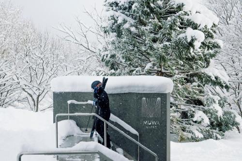 een persoon die op een reling in de sneeuw staat bij MUWA NISEKO in Kutchan