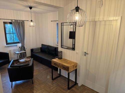 sala de estar con sofá negro y mesa en Mazurskie Siedlisko Langen, en Mrągowo